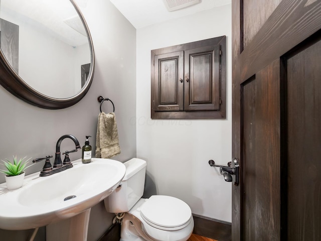 bathroom with a sink, toilet, and visible vents