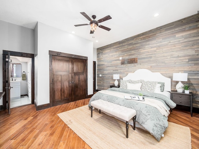 bedroom featuring recessed lighting, wood walls, light wood finished floors, and an accent wall