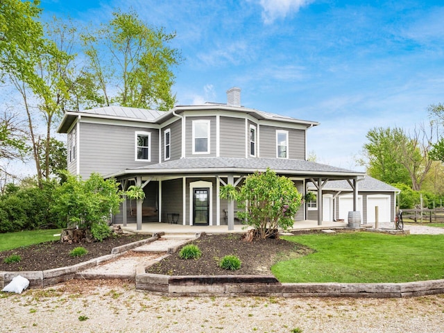 view of front of house with covered porch, a chimney, metal roof, a front yard, and a garage