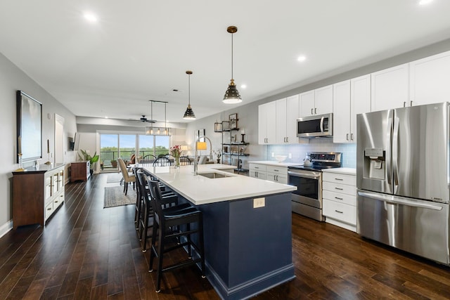kitchen with light countertops, dark wood finished floors, stainless steel appliances, and a kitchen breakfast bar