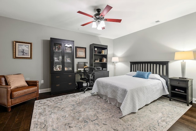 bedroom featuring baseboards, a ceiling fan, visible vents, and wood finished floors