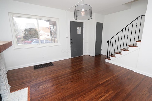 foyer entrance with baseboards, stairs, wood finished floors, and visible vents