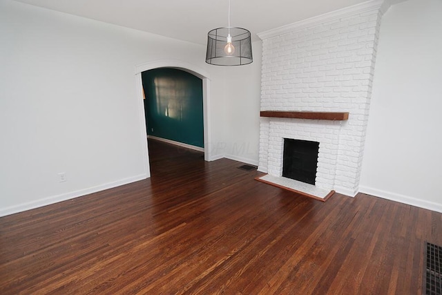 unfurnished living room featuring a brick fireplace, arched walkways, baseboards, wood finished floors, and visible vents