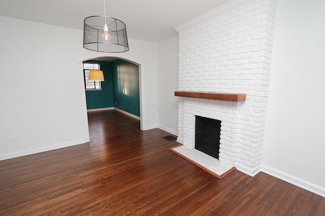 unfurnished living room featuring arched walkways, baseboards, a brick fireplace, and wood finished floors