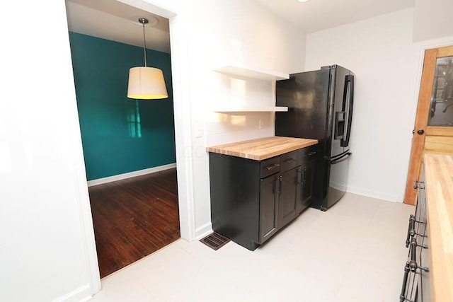 kitchen featuring wooden counters, decorative light fixtures, open shelves, baseboards, and black fridge
