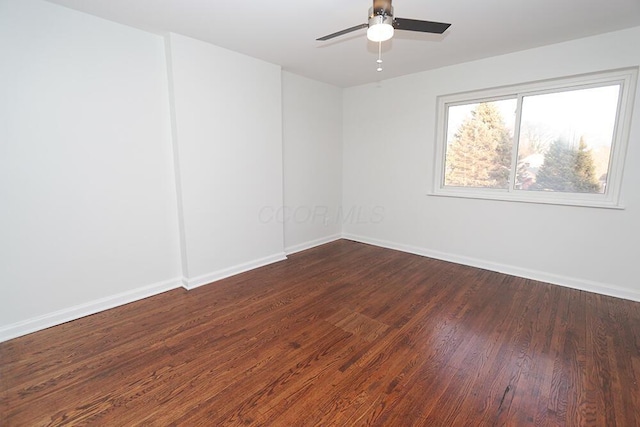 spare room with baseboards, dark wood-style flooring, and ceiling fan