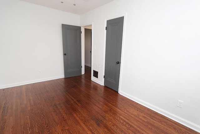 empty room featuring baseboards and dark wood-style flooring