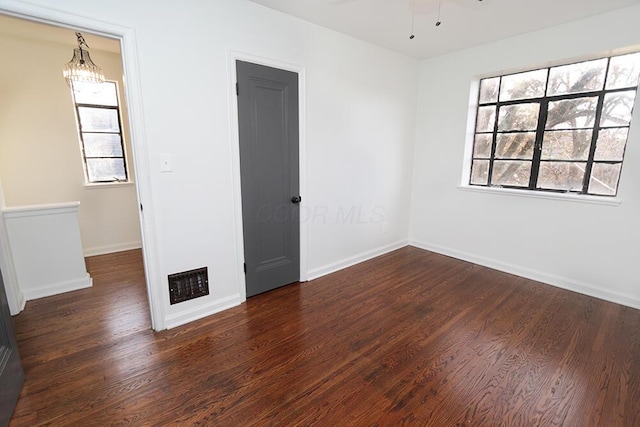 unfurnished room with baseboards, wood finished floors, and a healthy amount of sunlight