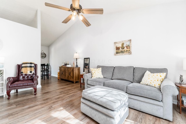 living area with a ceiling fan, high vaulted ceiling, and light wood-type flooring