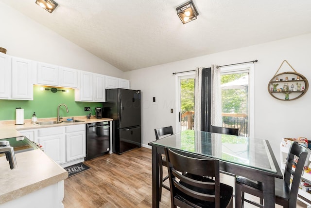 kitchen featuring a sink, light countertops, black appliances, and lofted ceiling