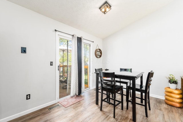dining room featuring visible vents, baseboards, and wood finished floors