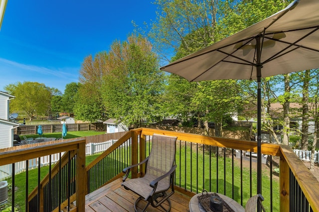 deck with a yard, an outdoor structure, central AC unit, and a fenced backyard