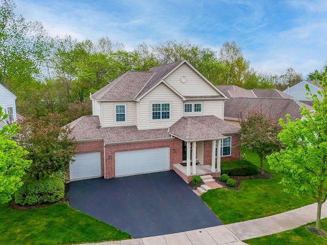 traditional-style house with a front yard, a garage, brick siding, aphalt driveway, and a shingled roof