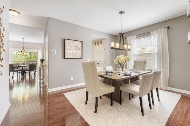 dining room featuring baseboards, wood finished floors, and a notable chandelier