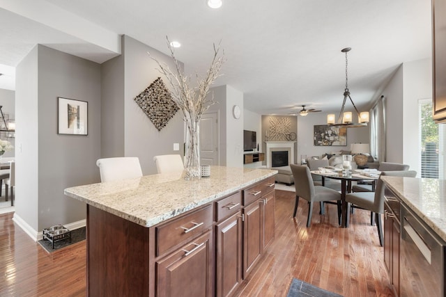 kitchen with ceiling fan, hanging light fixtures, light wood finished floors, and a fireplace