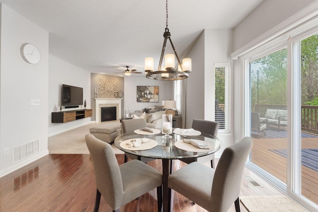 dining space featuring a notable chandelier, visible vents, wood finished floors, and a fireplace