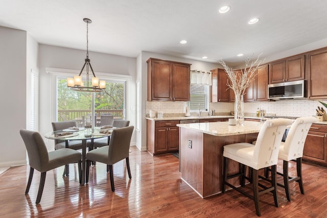 kitchen with stainless steel microwave, backsplash, dark wood-type flooring, and a notable chandelier