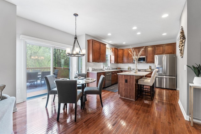 kitchen featuring backsplash, pendant lighting, a center island, dark wood-style floors, and stainless steel appliances