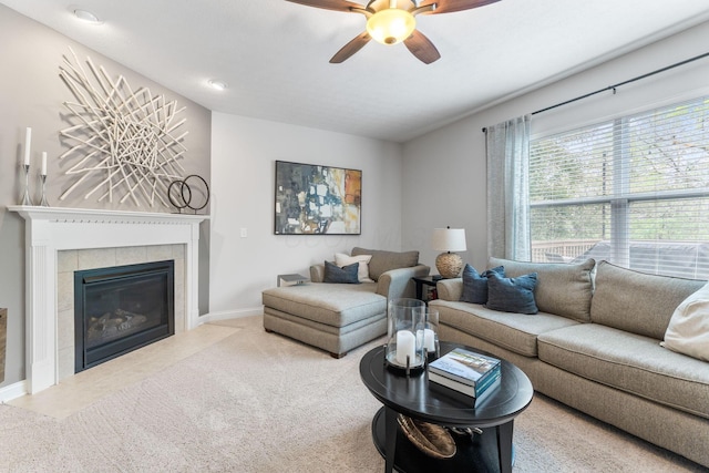 living area with carpet floors, baseboards, ceiling fan, and a tiled fireplace