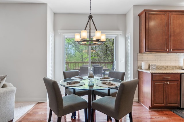 dining area with light wood-style floors, baseboards, and a chandelier