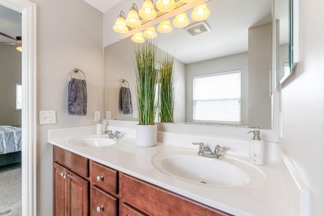bathroom with double vanity, a ceiling fan, a sink, and ensuite bathroom