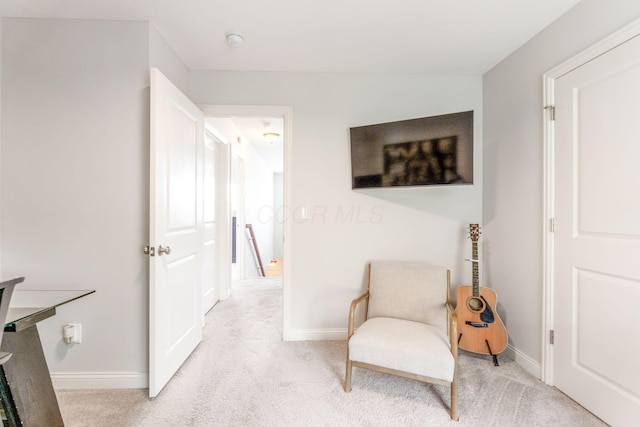sitting room featuring baseboards and light colored carpet