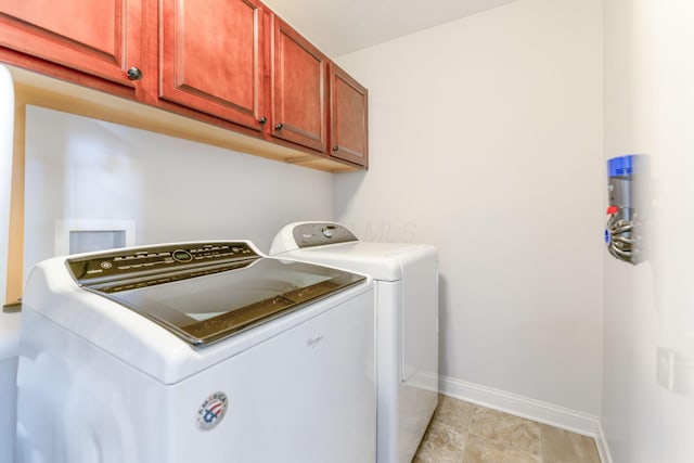 clothes washing area featuring baseboards, cabinet space, light tile patterned flooring, and washer and dryer