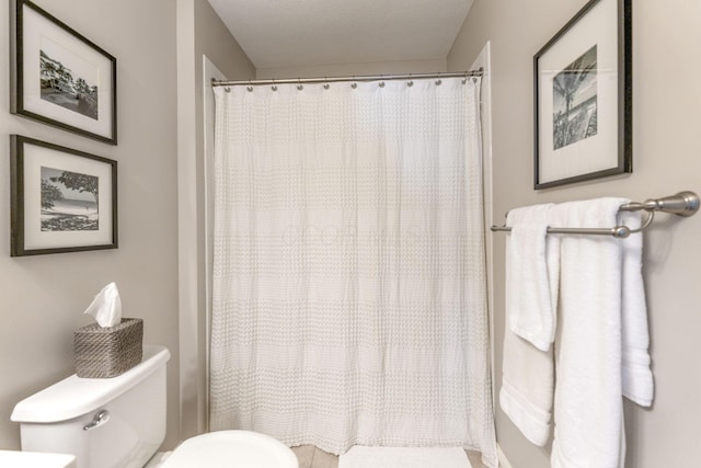 bathroom featuring toilet and curtained shower