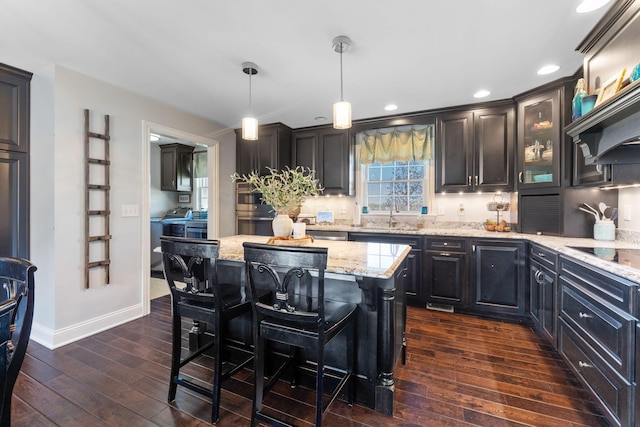 1012 Lake Fork Rd, Utica, OH 43080 - kitchen with light stone countertops, black electric stovetop, a sink, a breakfast bar area, and dark wood-style floors