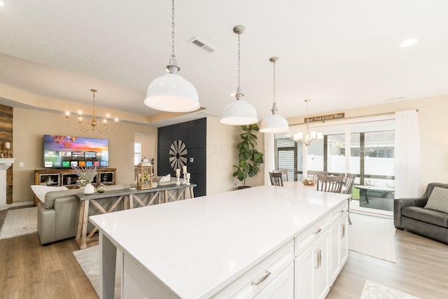 kitchen with light wood-style flooring, a center island, an inviting chandelier, visible vents, and open floor plan