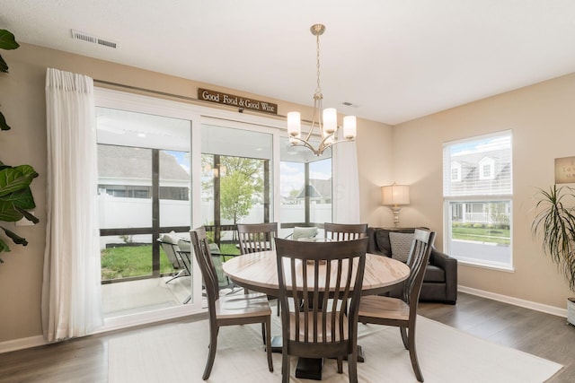 dining room with a chandelier, baseboards, visible vents, and wood finished floors