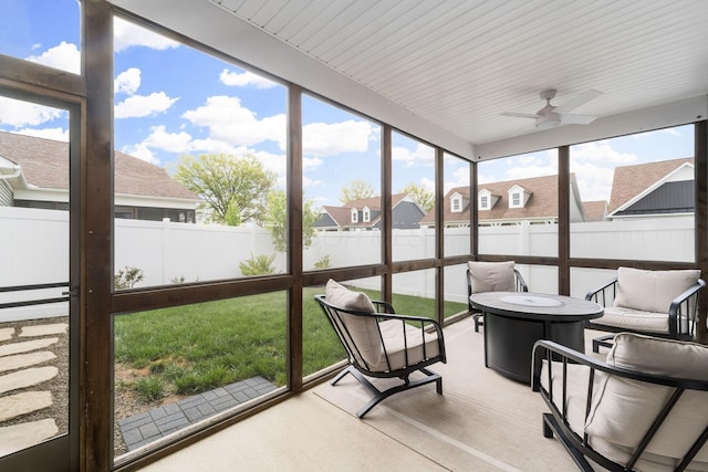 sunroom / solarium with ceiling fan, a fire pit, and a residential view
