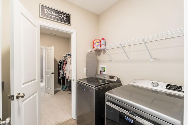 clothes washing area featuring laundry area, light colored carpet, baseboards, and washer and dryer