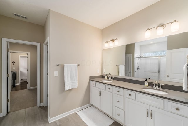 full bathroom with double vanity, visible vents, a shower stall, and a sink