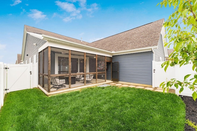 rear view of house featuring a yard, a sunroom, roof with shingles, a fenced backyard, and a gate