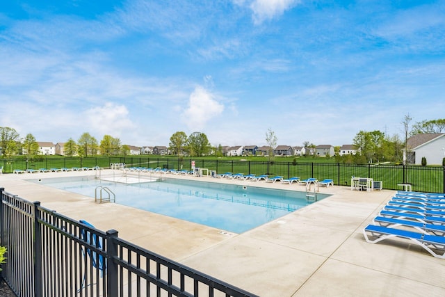 pool with a patio area, fence, and a residential view