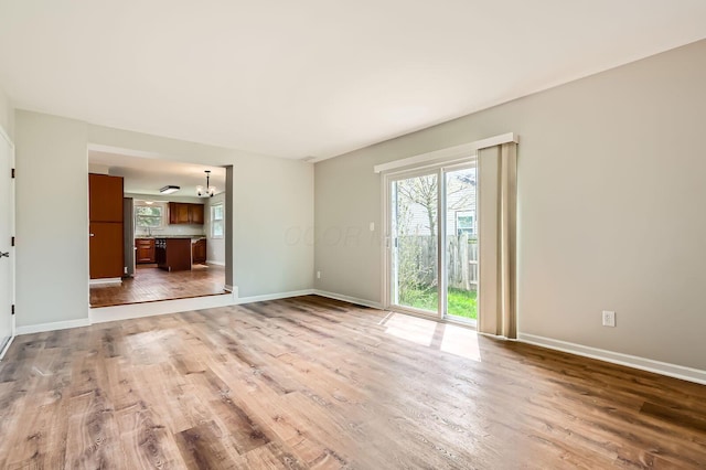 3861 Trestle Ct, Columbus, OH 43204 - unfurnished living room featuring wood finished floors, baseboards, and a chandelier