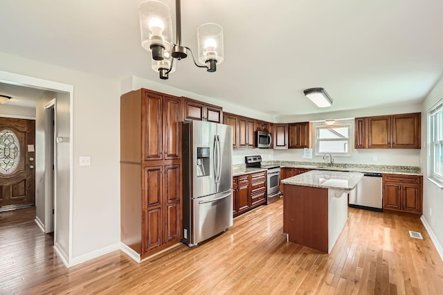 3861 Trestle Ct, Columbus, OH 43204 - kitchen with appliances with stainless steel finishes, a sink, light wood finished floors, light stone countertops, and a center island