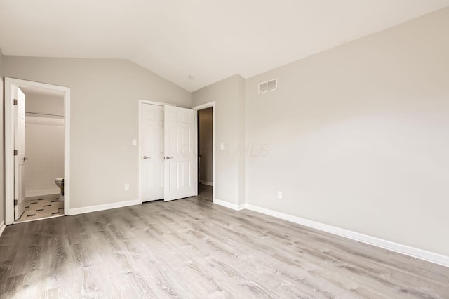 3861 Trestle Ct, Columbus, OH 43204 - unfurnished bedroom featuring wood finished floors, vaulted ceiling, baseboards, and connected bathroom