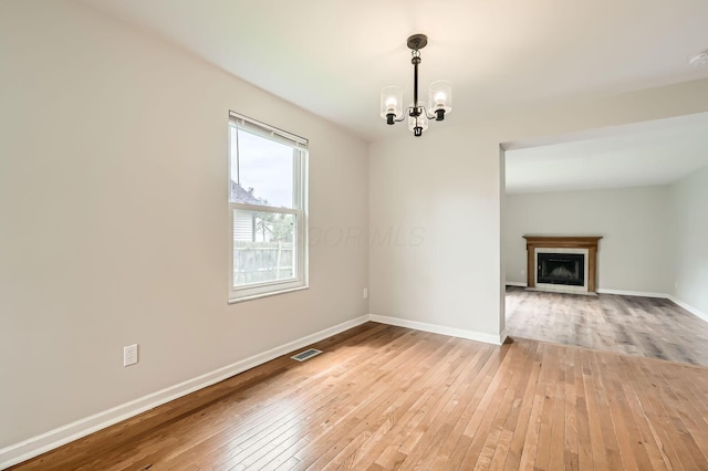 3861 Trestle Ct, Columbus, OH 43204 - unfurnished dining area featuring light wood finished floors, a chandelier, baseboards, and a fireplace