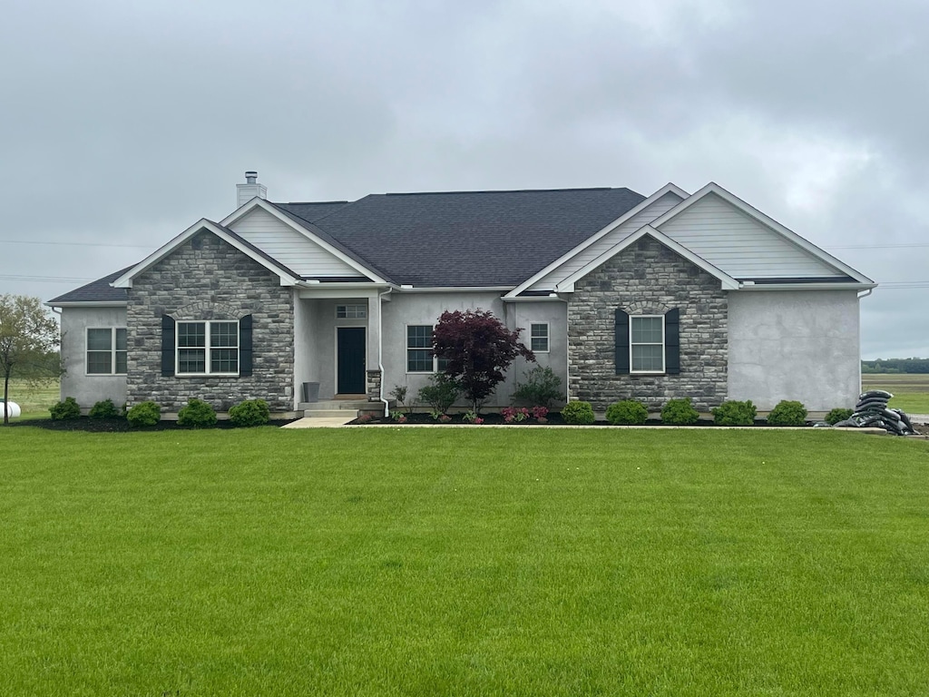 view of front of home with a chimney, stucco siding, a front yard, and stone siding