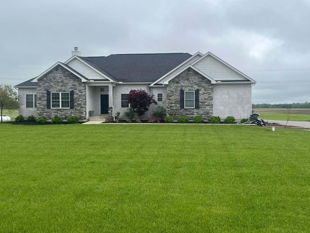 ranch-style home featuring stucco siding, a front lawn, and stone siding