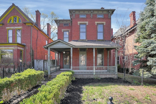 italianate-style house featuring a porch, fence, and brick siding