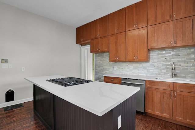 kitchen with black gas stovetop, a sink, dishwasher, dark wood finished floors, and backsplash