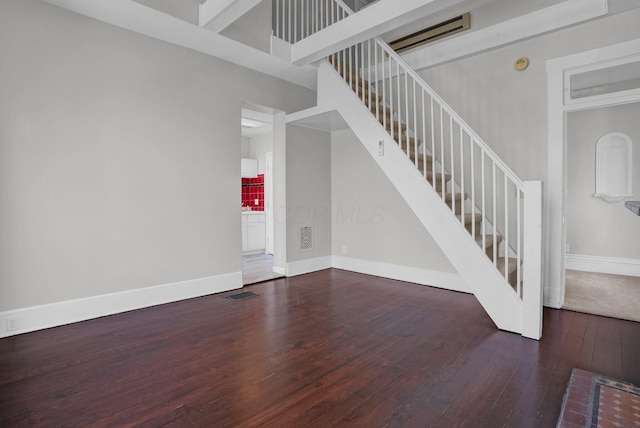 interior space featuring stairway, baseboards, visible vents, and hardwood / wood-style flooring