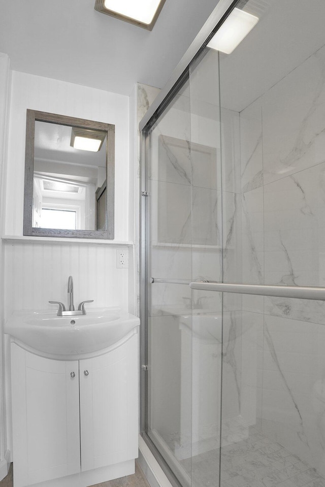 full bath with a marble finish shower and vanity