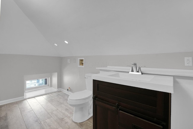 bathroom featuring toilet, wood finished floors, lofted ceiling, and vanity