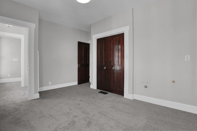 unfurnished bedroom with carpet floors, baseboards, visible vents, and a closet