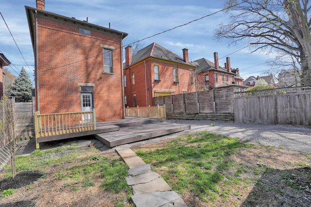 back of house featuring brick siding, a fenced backyard, and a deck