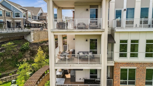 rear view of house with brick siding, a balcony, stucco siding, and a residential view
